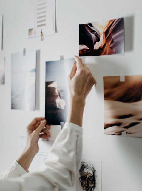 tow hands holding corners of photo taped to wall